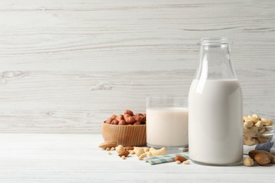 Photo of Different nut milks on white wooden table. Space for text