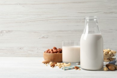 Different nut milks on white wooden table. Space for text