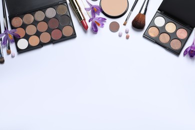 Flat lay composition with eyeshadow palettes and beautiful crocuses on white background, space for text