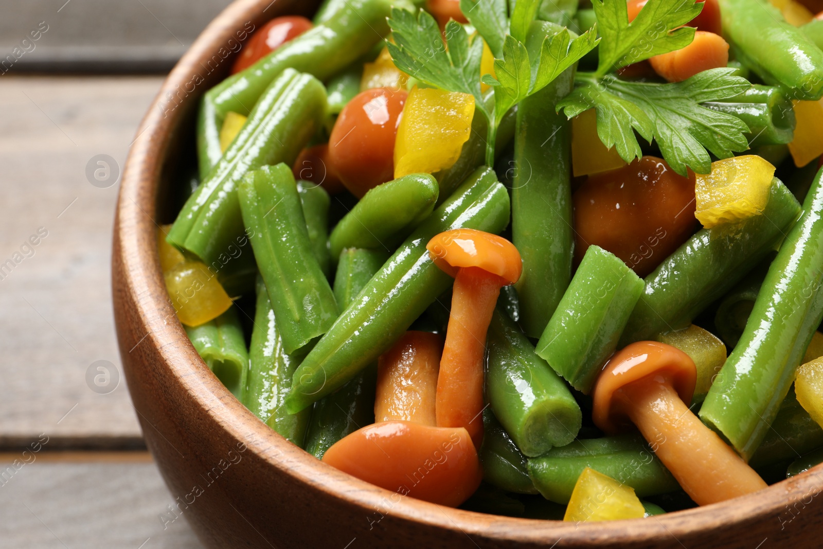 Photo of Bowl of tasty salad with green beans on wooden table, closeup