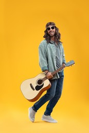 Photo of Stylish hippie man with guitar on orange background