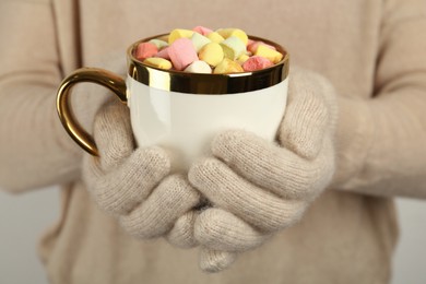 Photo of Woman in woolen gloves holding cup of delicious hot chocolate with marshmallows, closeup