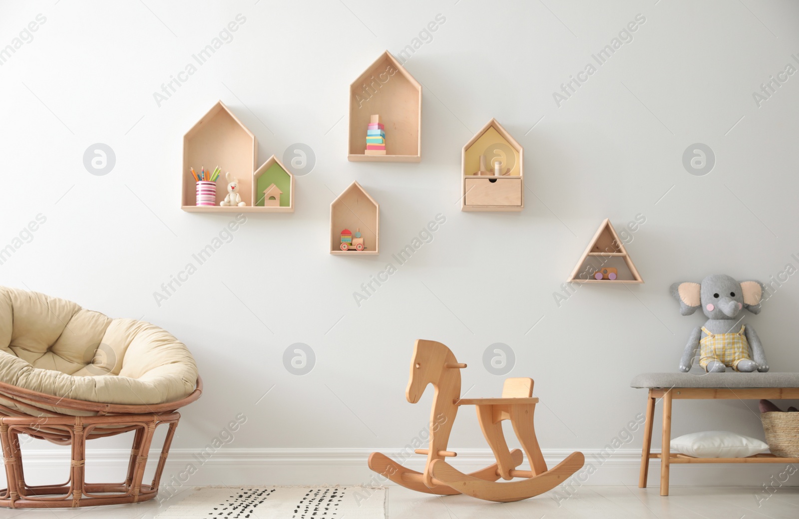 Photo of House shaped shelves and rocking horse in children's room. Interior design