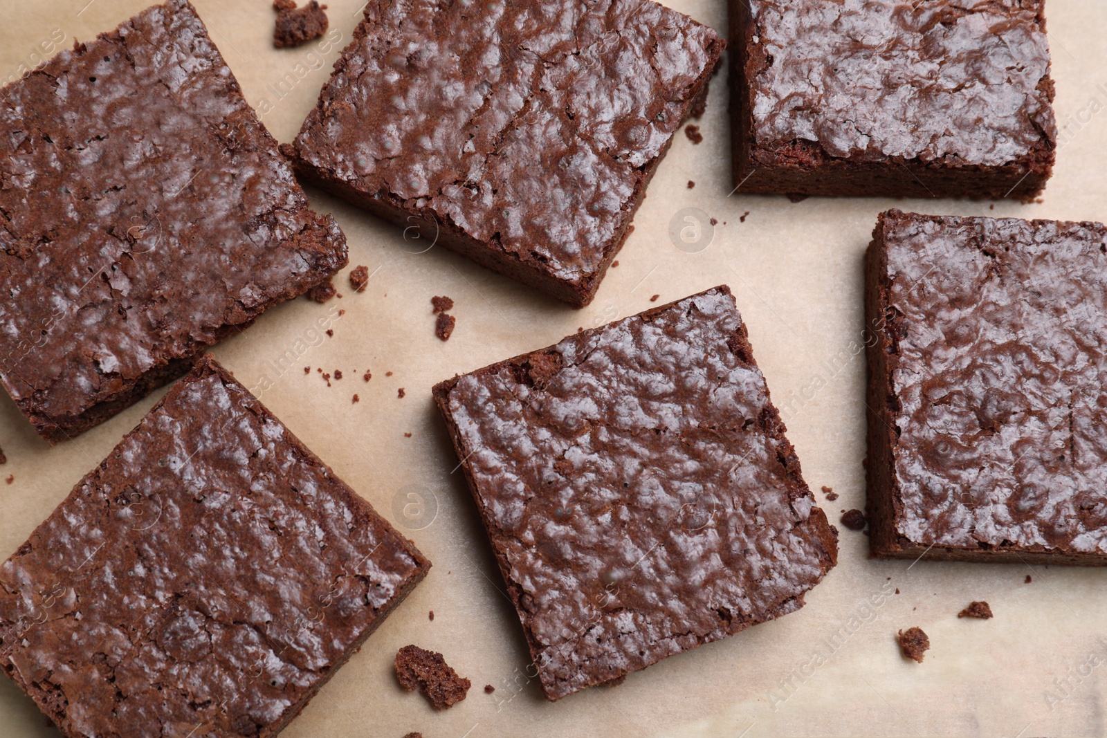 Photo of Delicious chocolate brownies on parchment paper, top view