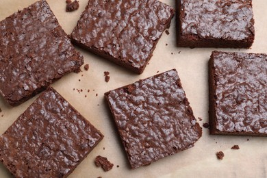 Photo of Delicious chocolate brownies on parchment paper, top view