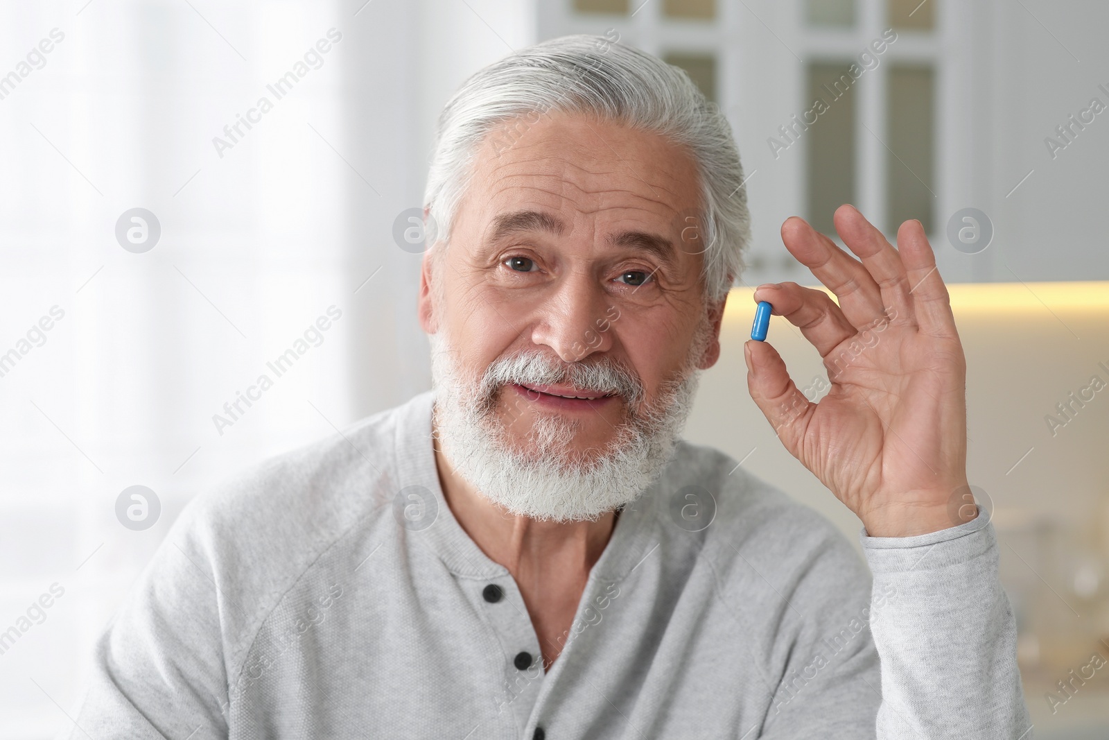 Photo of Handsome senior man with pill at home