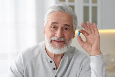 Photo of Handsome senior man with pill at home