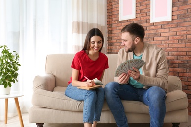 Photo of Beautiful young couple with money at home