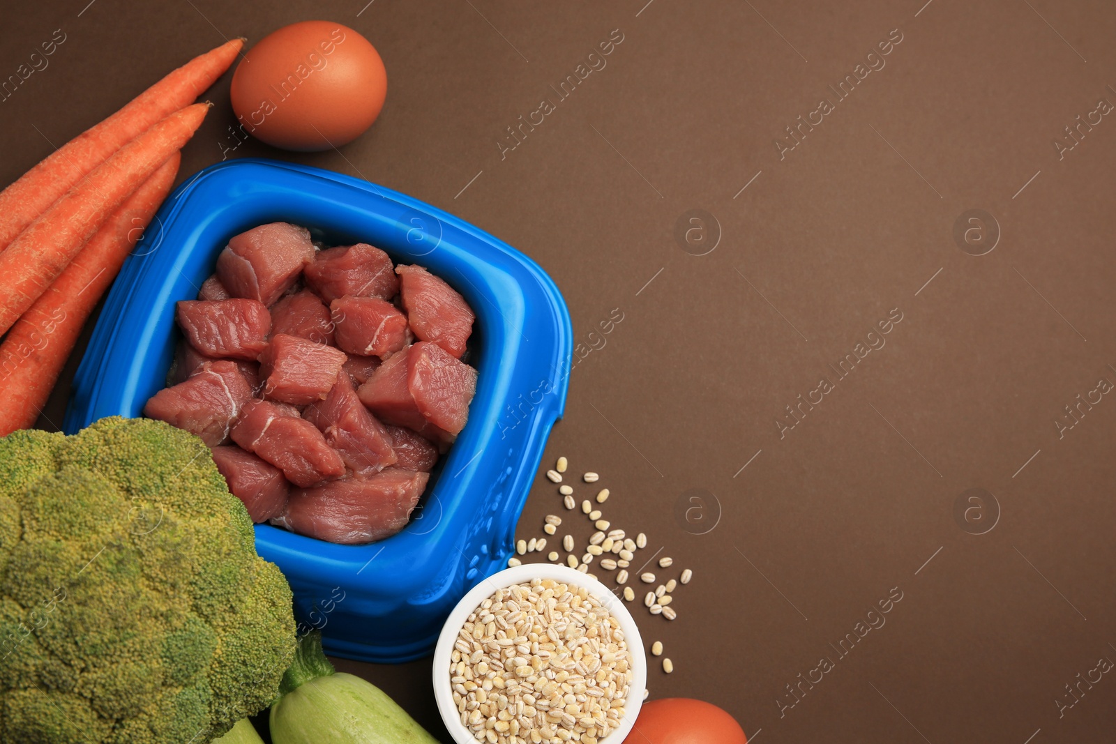 Photo of Raw meat in bowl and healthy products for pet on brown background, flat lay. Space for text