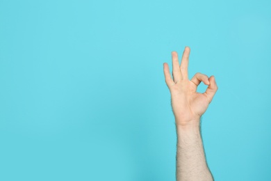 Photo of Young man showing OK gesture on color background. Space for text