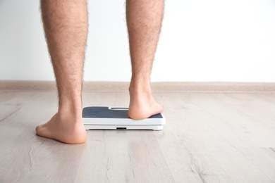 Photo of Overweight man measuring his weight indoors