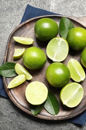 Fresh ripe limes and leaves on grey table, top view