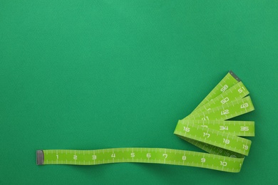 Measuring tape on green background, top view. Space for text