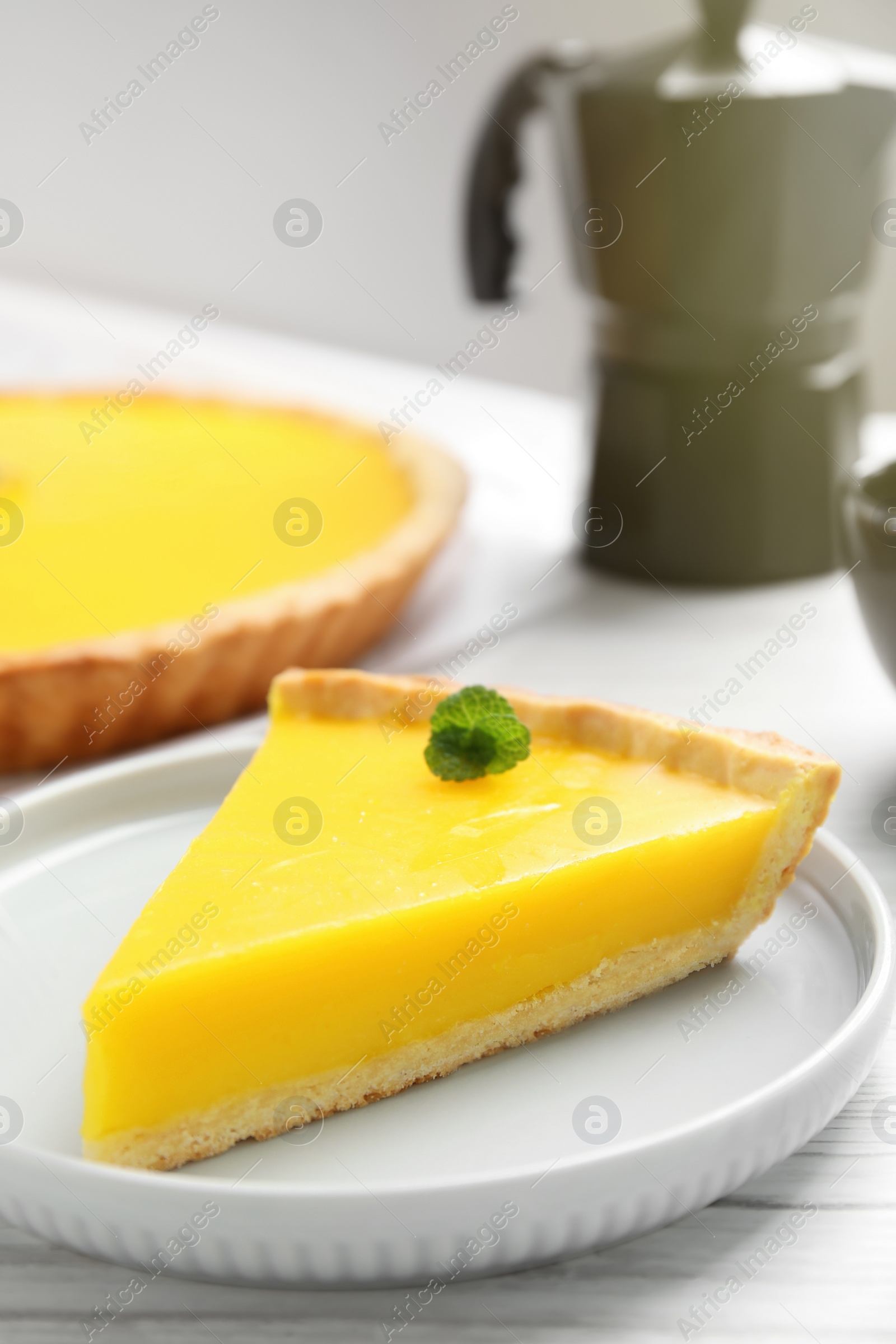 Photo of Slice of delicious homemade lemon pie on white wooden table