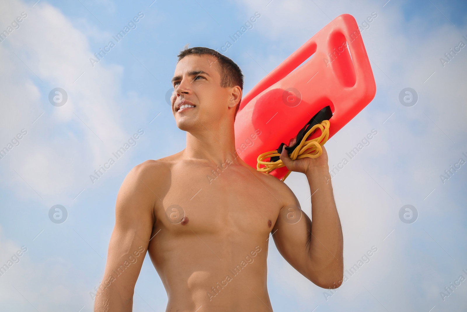 Photo of Handsome lifeguard with life buoy against blue sky