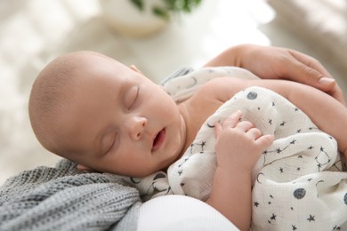 Mother holding her sleeping baby indoors, closeup