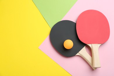 Photo of Ping pong rackets and ball on color background, flat lay. Space for text