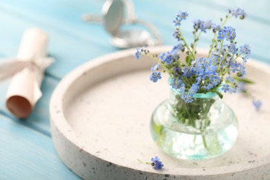 Photo of Beautiful  Forget-me-not flowers in vase on light blue wooden table. Space for text