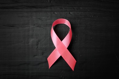 Pink ribbon on wooden background, top view. Breast cancer concept