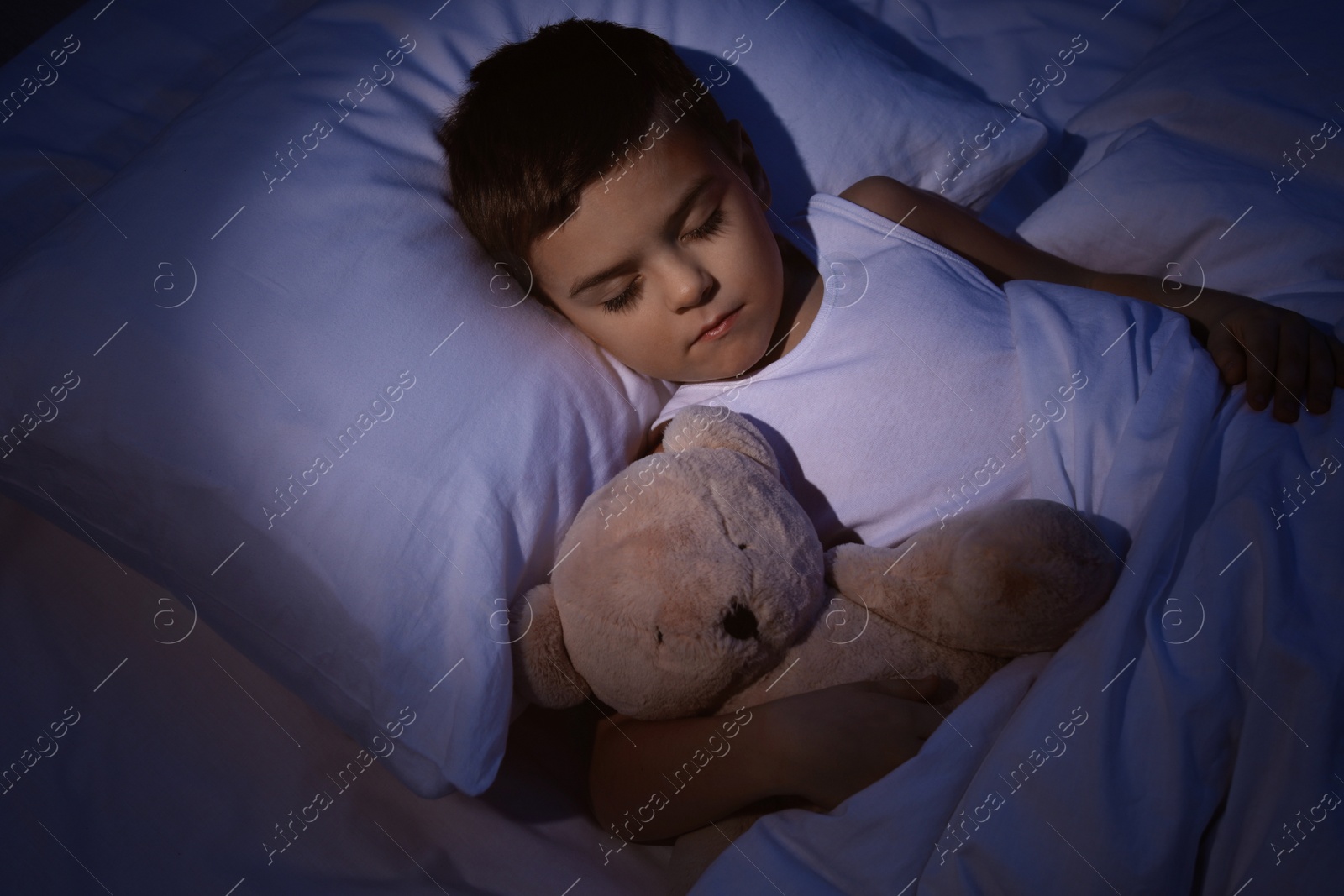 Photo of Little boy sleeping with teddy bear at home. Bedtime