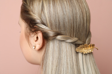 Photo of Young woman with beautiful gold hair clip on pink background, closeup