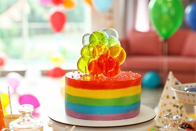 Bright birthday cake on table in decorated room