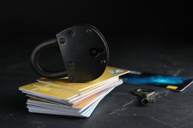 Credit cards, padlock and key on black slate table. Protection from cyber attack