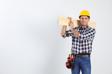Photo of Handsome carpenter with wooden planks on light background. Space for text