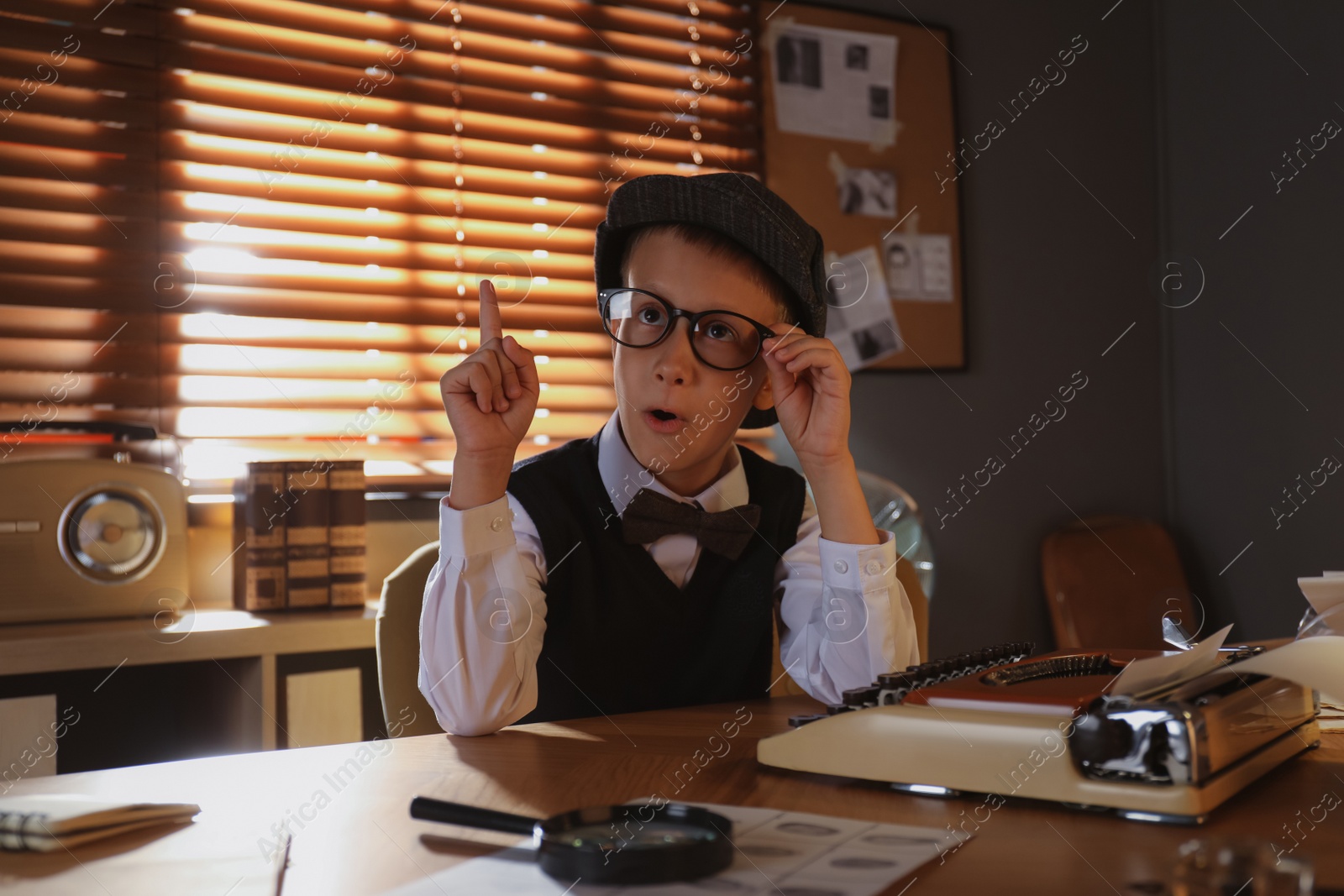 Photo of Cute little detective wearing glasses at table in office