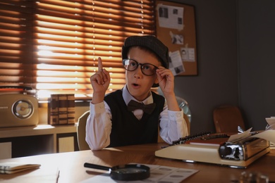 Cute little detective wearing glasses at table in office