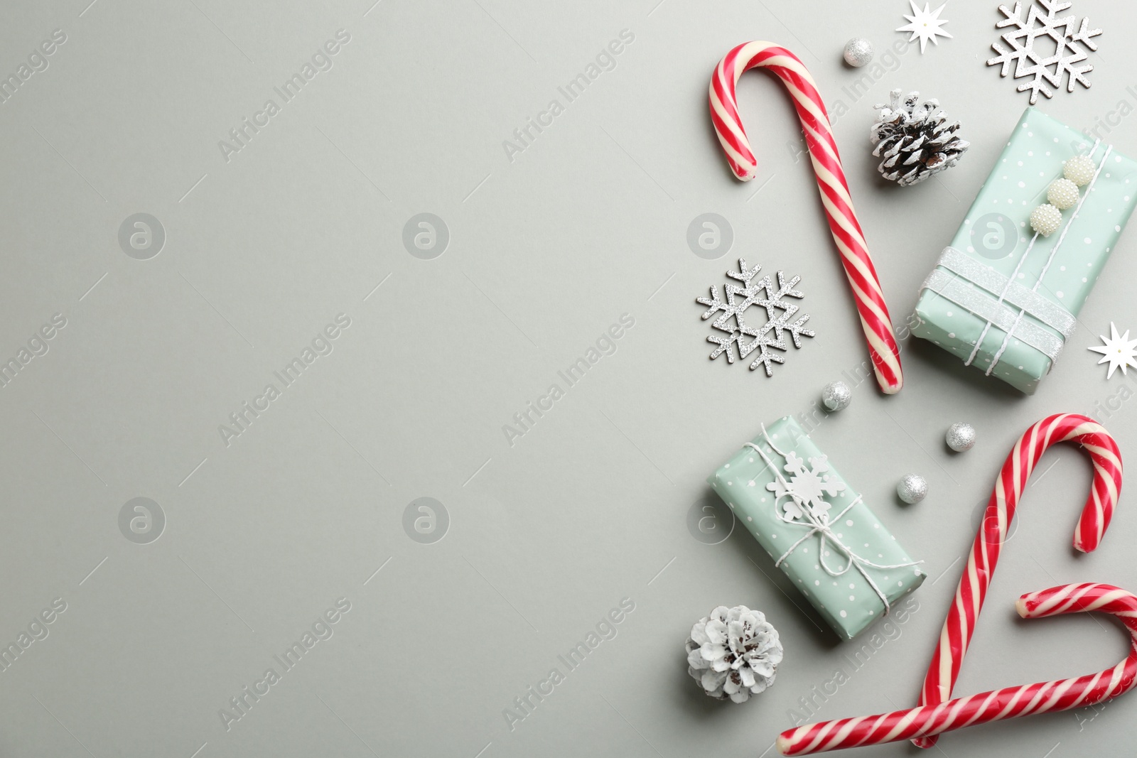Photo of Flat lay composition with candy canes and Christmas decor on grey background. Space for text