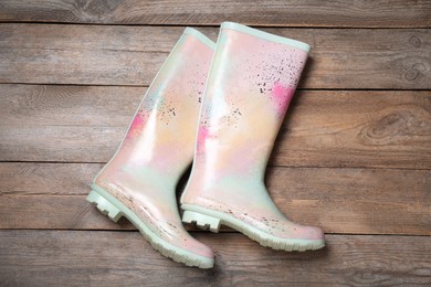 Photo of Pair of colorful rubber boots on wooden background, top view