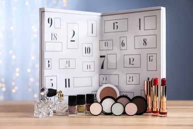 Photo of Christmas advent calendar with perfumes and makeup products on table