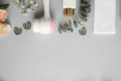 Flat lay composition with face cleansing brush on light grey background. Cosmetic accessory