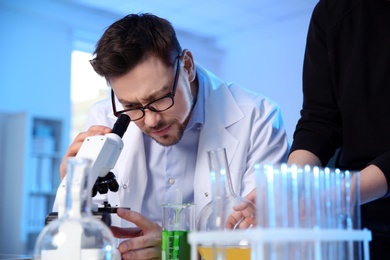 Male scientist using modern microscope in chemistry laboratory