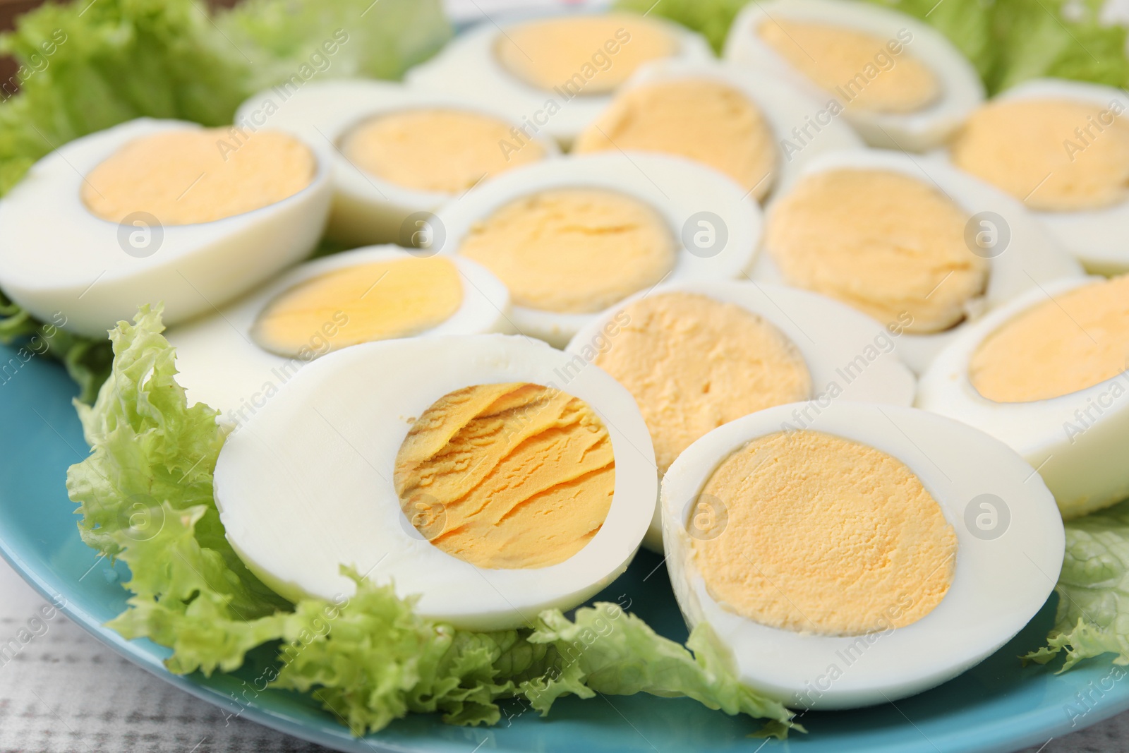 Photo of Fresh hard boiled eggs and lettuce on white wooden table, closeup
