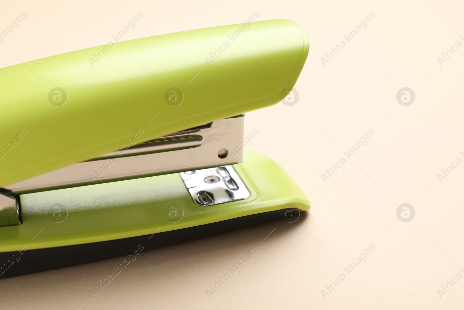 Photo of One bright stapler on beige background, closeup. Space for text