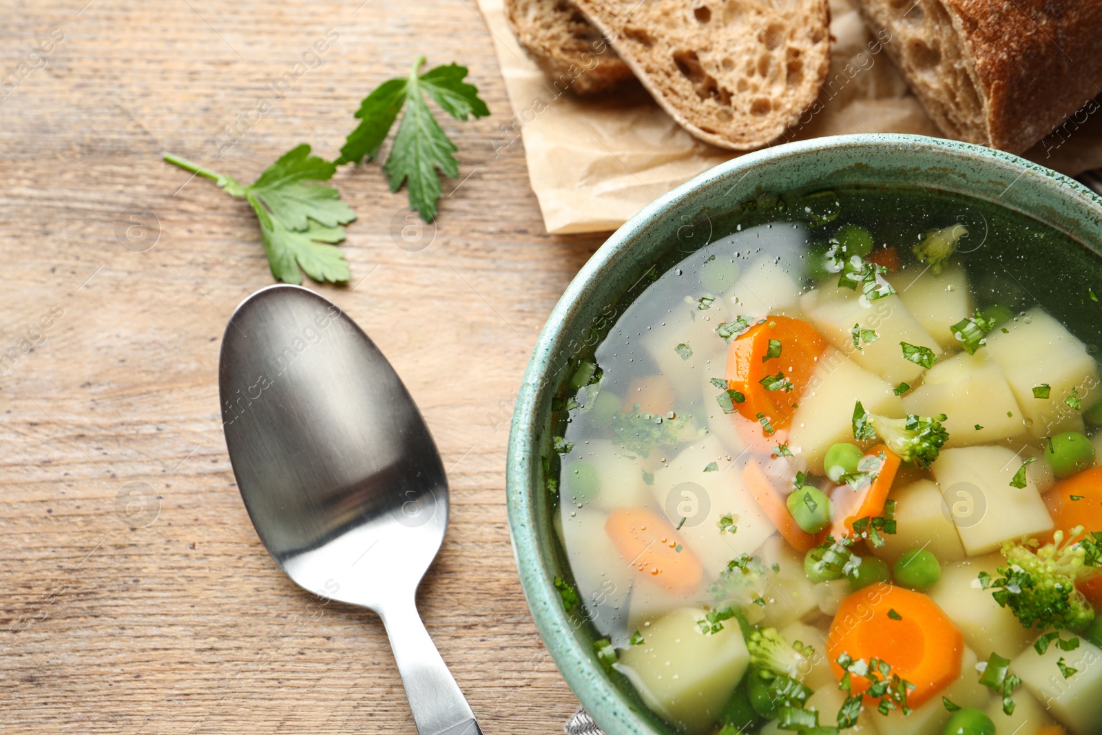 Photo of Bowl of fresh homemade vegetable soup served on wooden table, top view