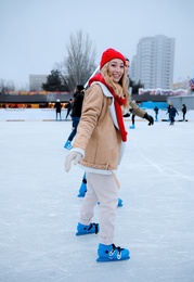 Image of Happy young woman skating at outdoor ice rink