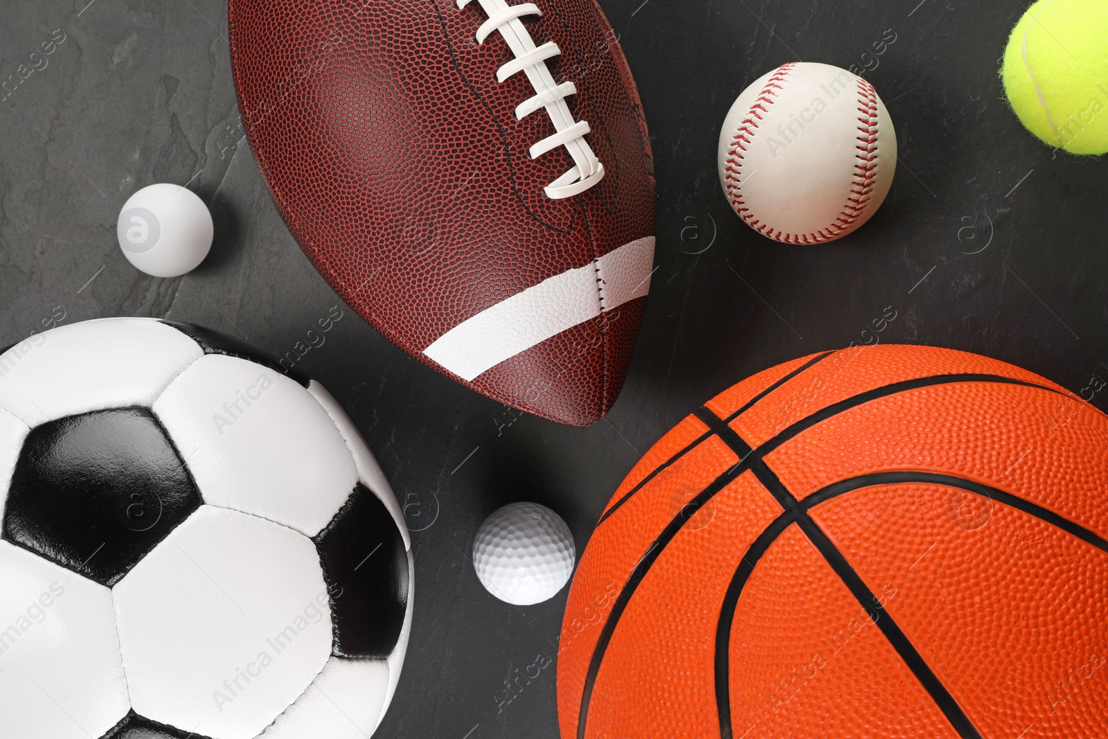 Photo of Many different sports balls on dark gray background, flat lay