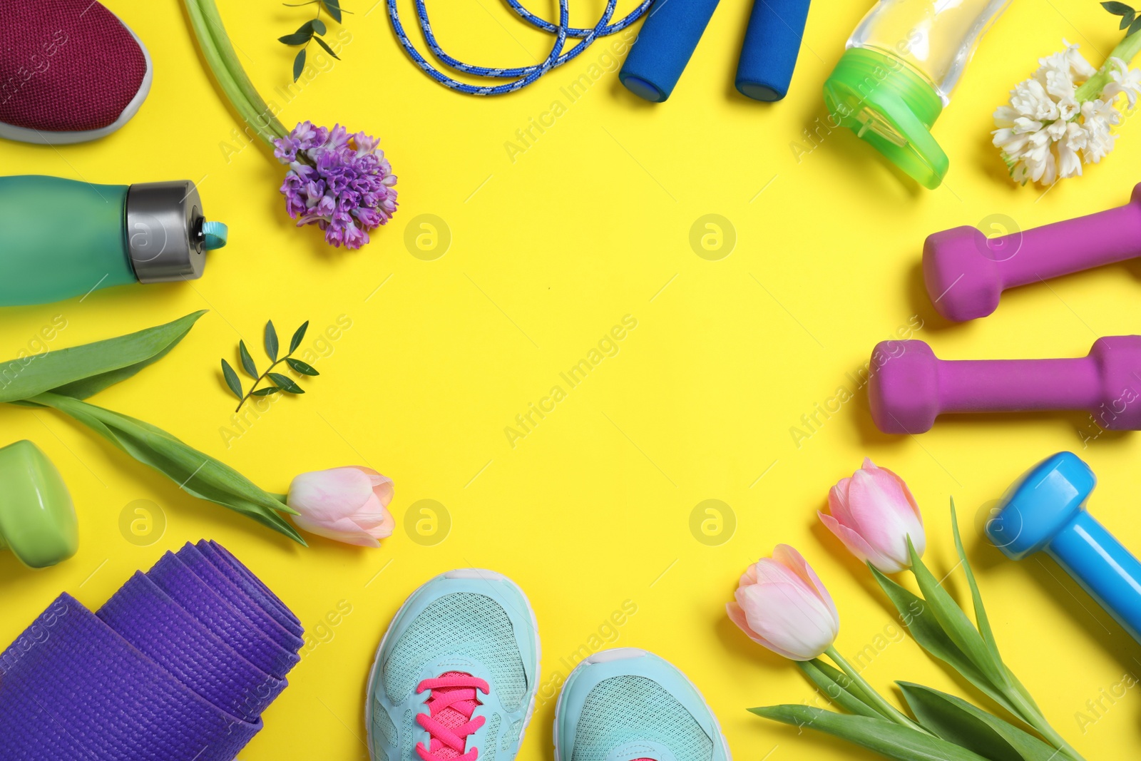 Photo of Frame made with spring flowers and sports items on yellow background, flat lay. Space for text