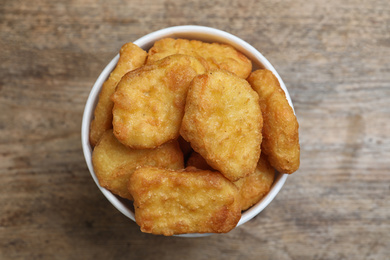 Photo of Bucket with tasty chicken nuggets on wooden table, top view