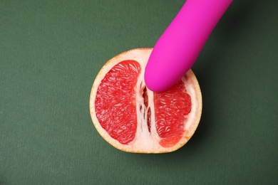Photo of Half of grapefruit and purple vibrator on dark grey background, flat lay. Sex concept