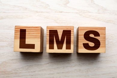 Image of Learning management system. Cubes with abbreviation LMS on wooden background, top view