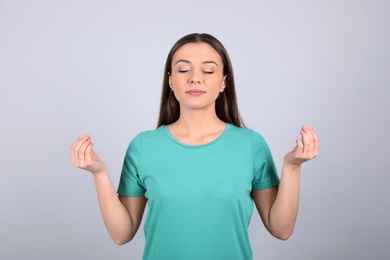 Photo of Young woman meditating on light background. Stress relief exercise