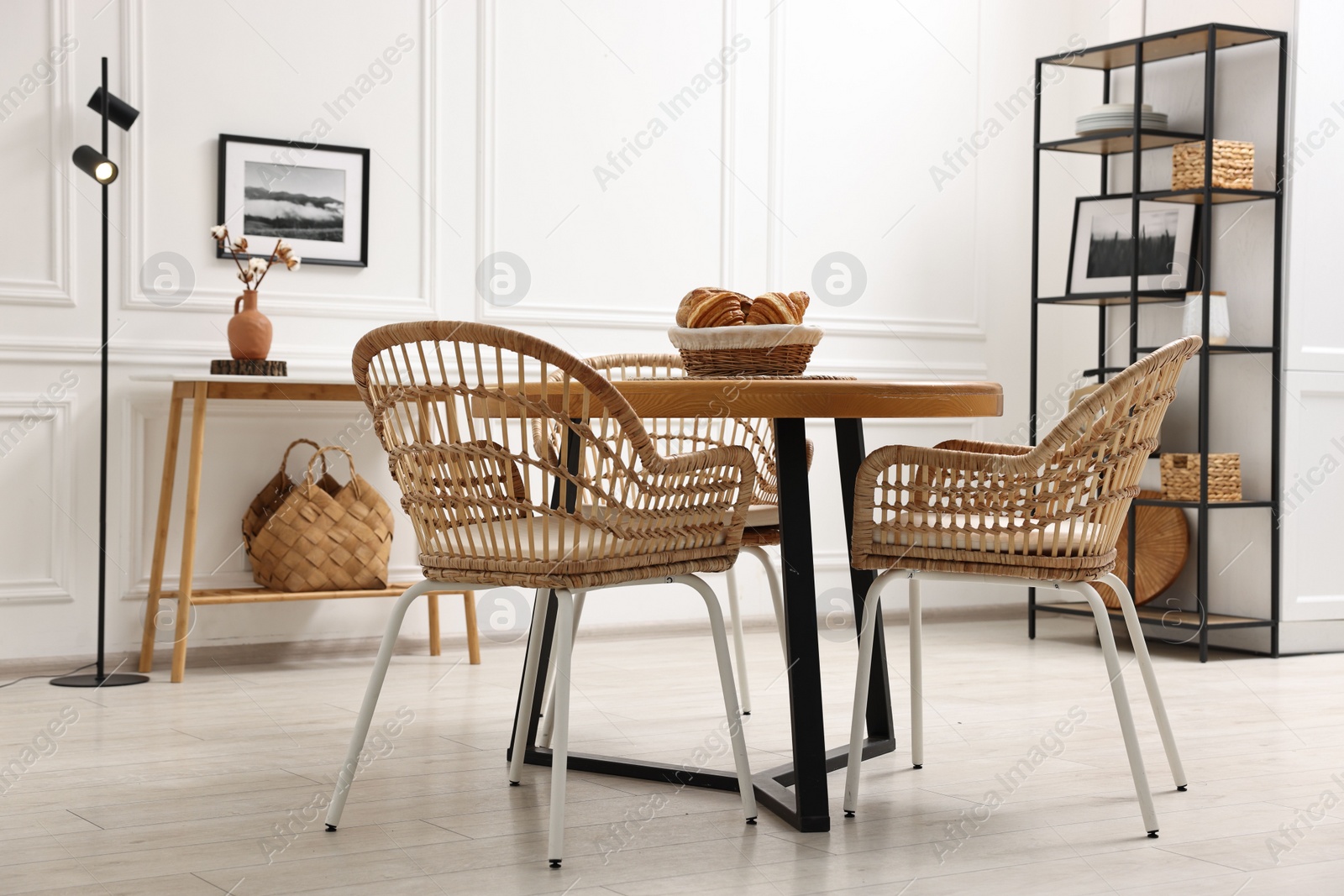 Photo of Dining room interior with wooden table and wicker chairs