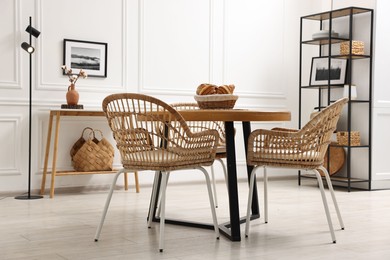 Photo of Dining room interior with wooden table and wicker chairs