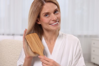 Beautiful happy woman brushing her hair in bedroom