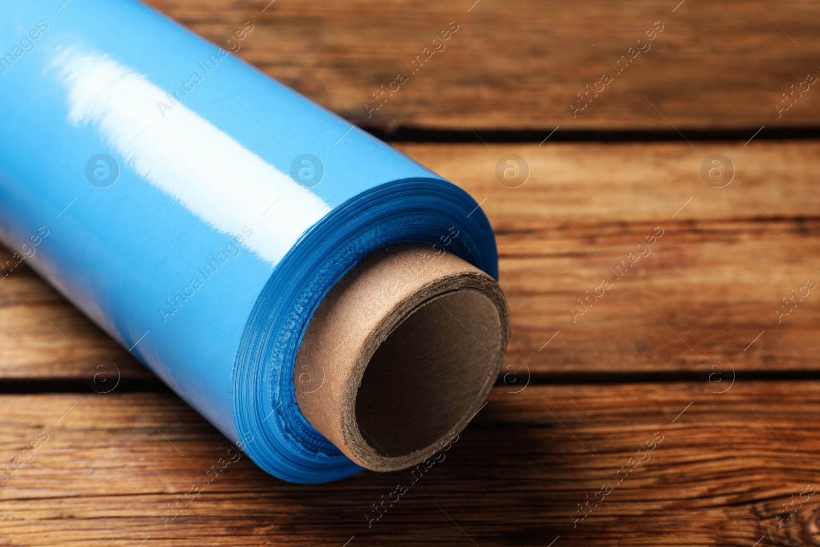 Photo of Roll of plastic stretch wrap film on wooden table, closeup