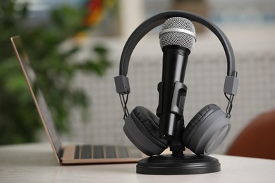Photo of Microphone, modern headphones and laptop on table indoors